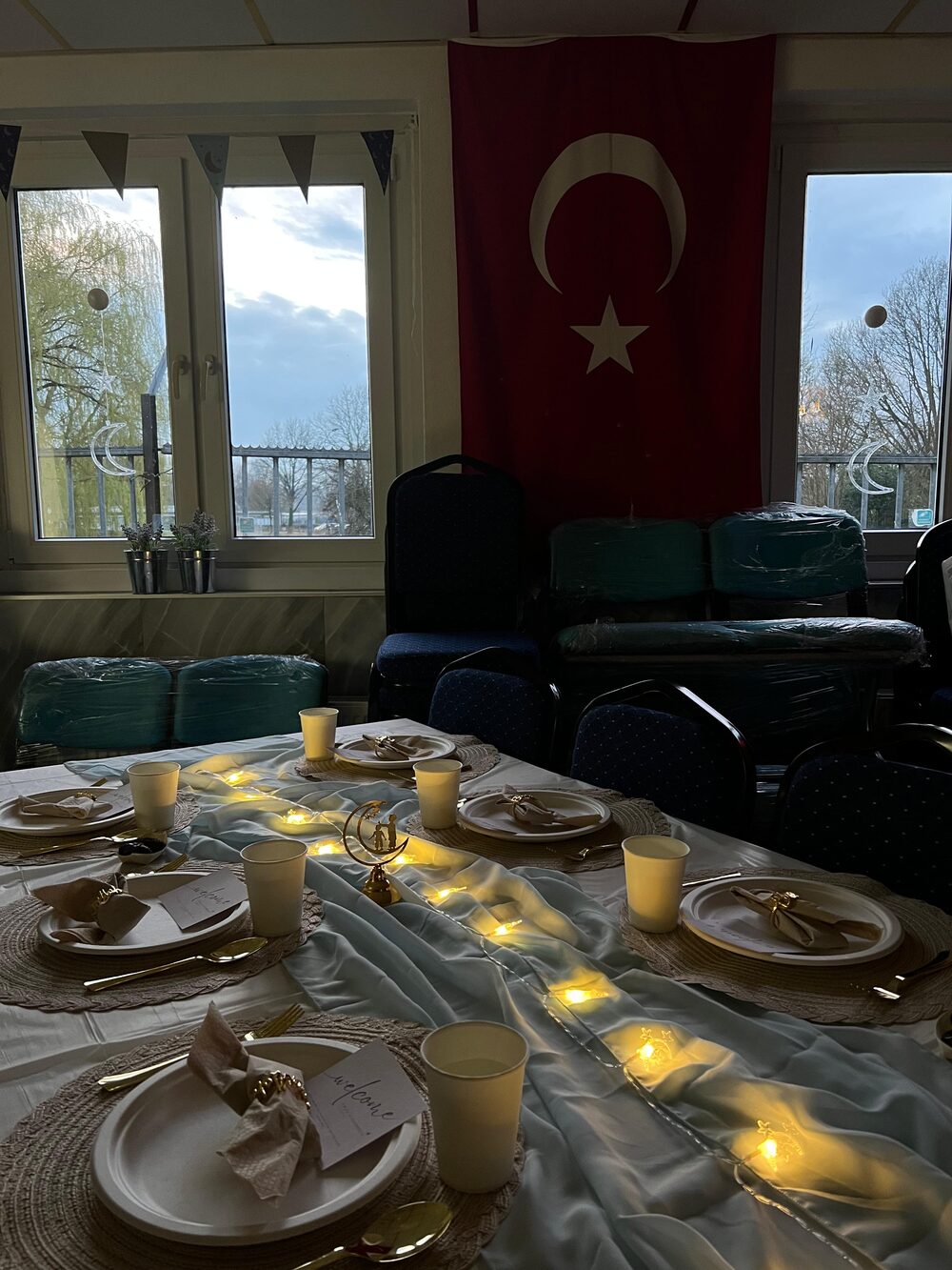 De zaal met gedekte tafels en lichtjes, klaar voor de iftar