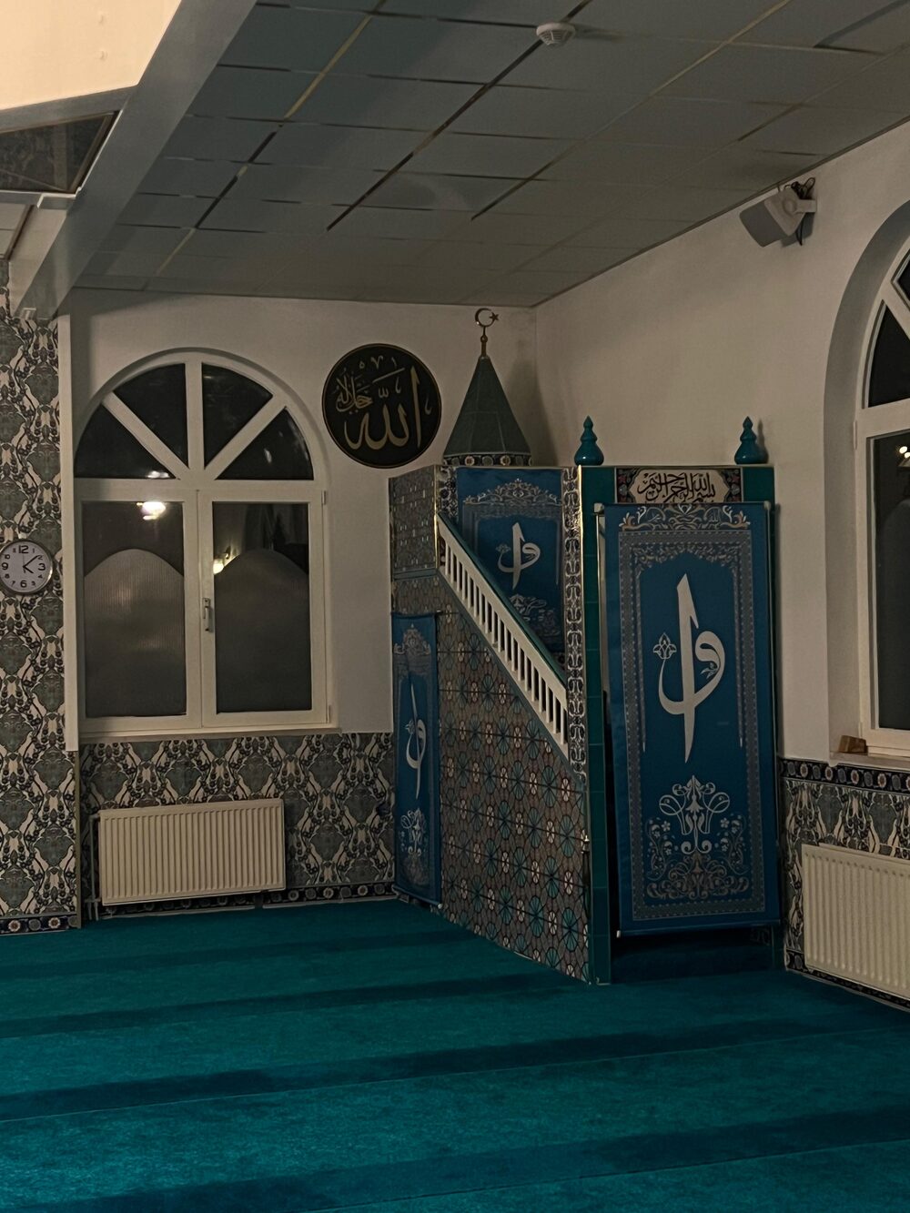 De minbar met blauwe tegels en kalligrafie, naast een boogvenster