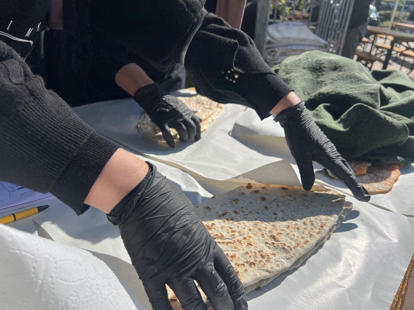 Handen in zwarte handschoenen vouwen verse gözleme op de kermes