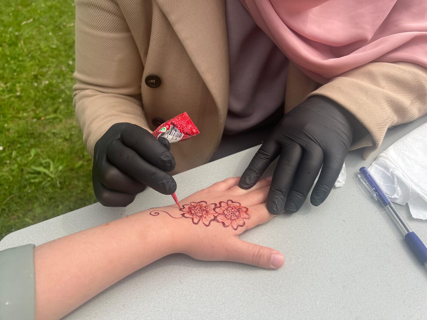 Een bloemmotief in henna wordt op een kinderhand getekend