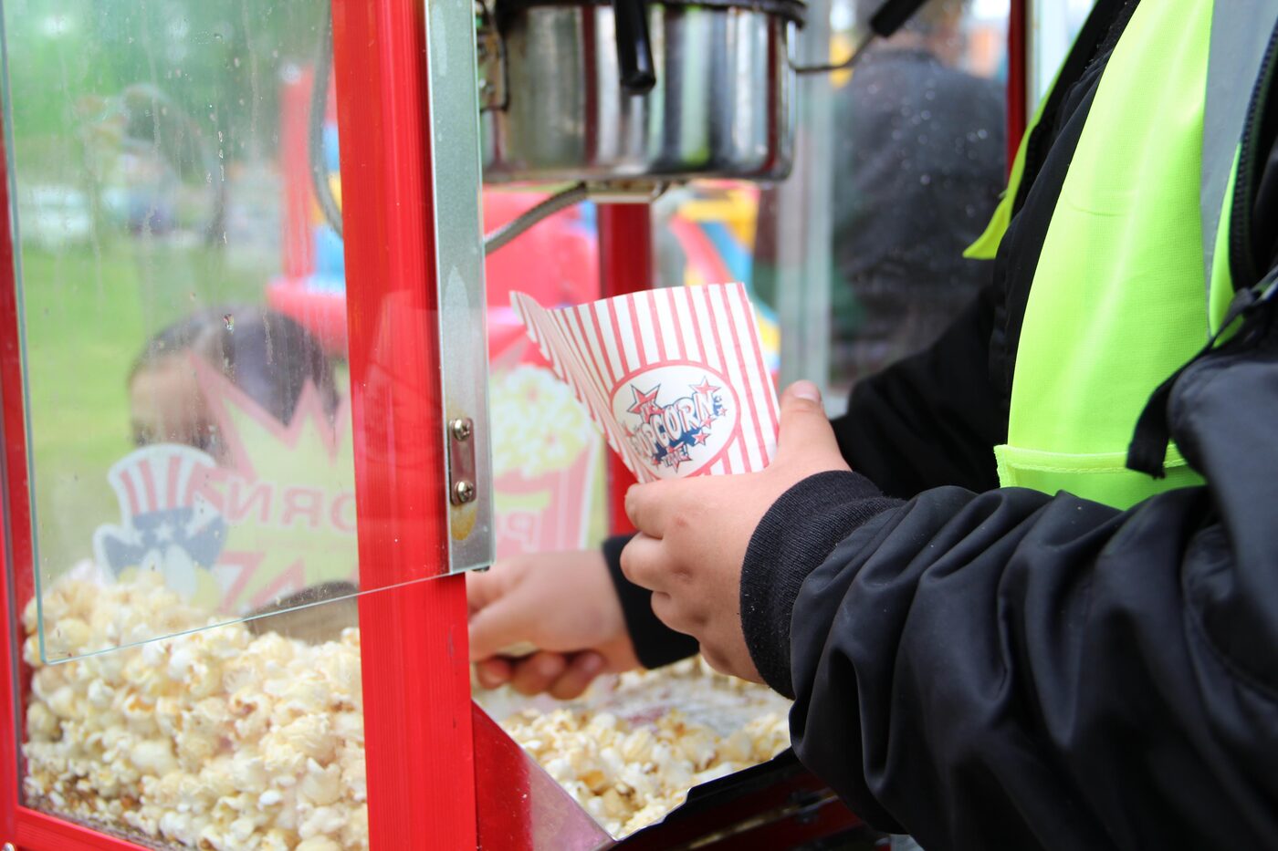 Een kind krijgt een bakje popcorn bij de popcornmachine