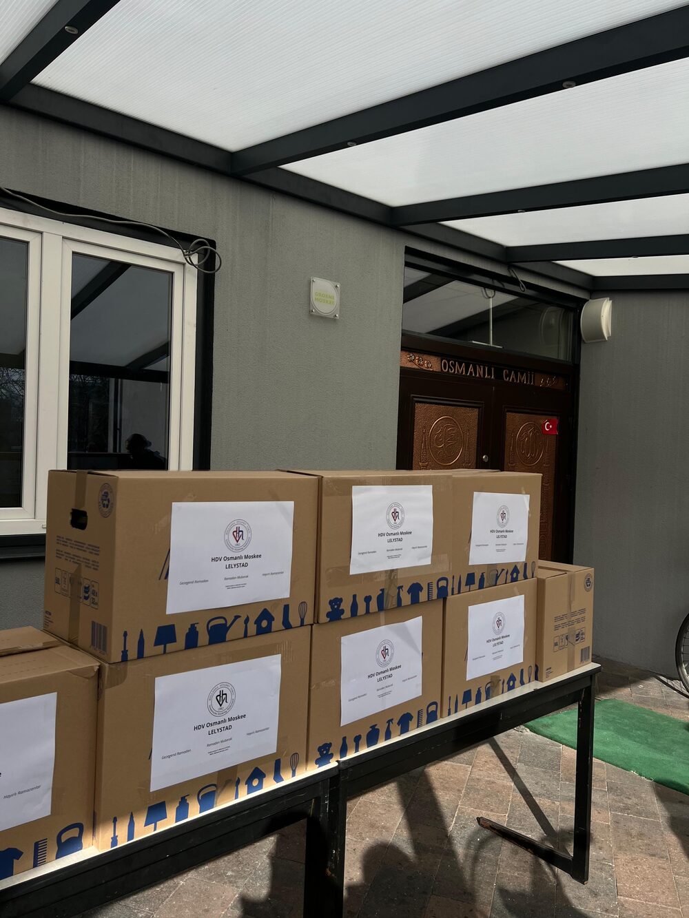 Dozen met ramadanpakketten van HDV Osmanlı Moskee Lelystad voor de ingang van de moskee